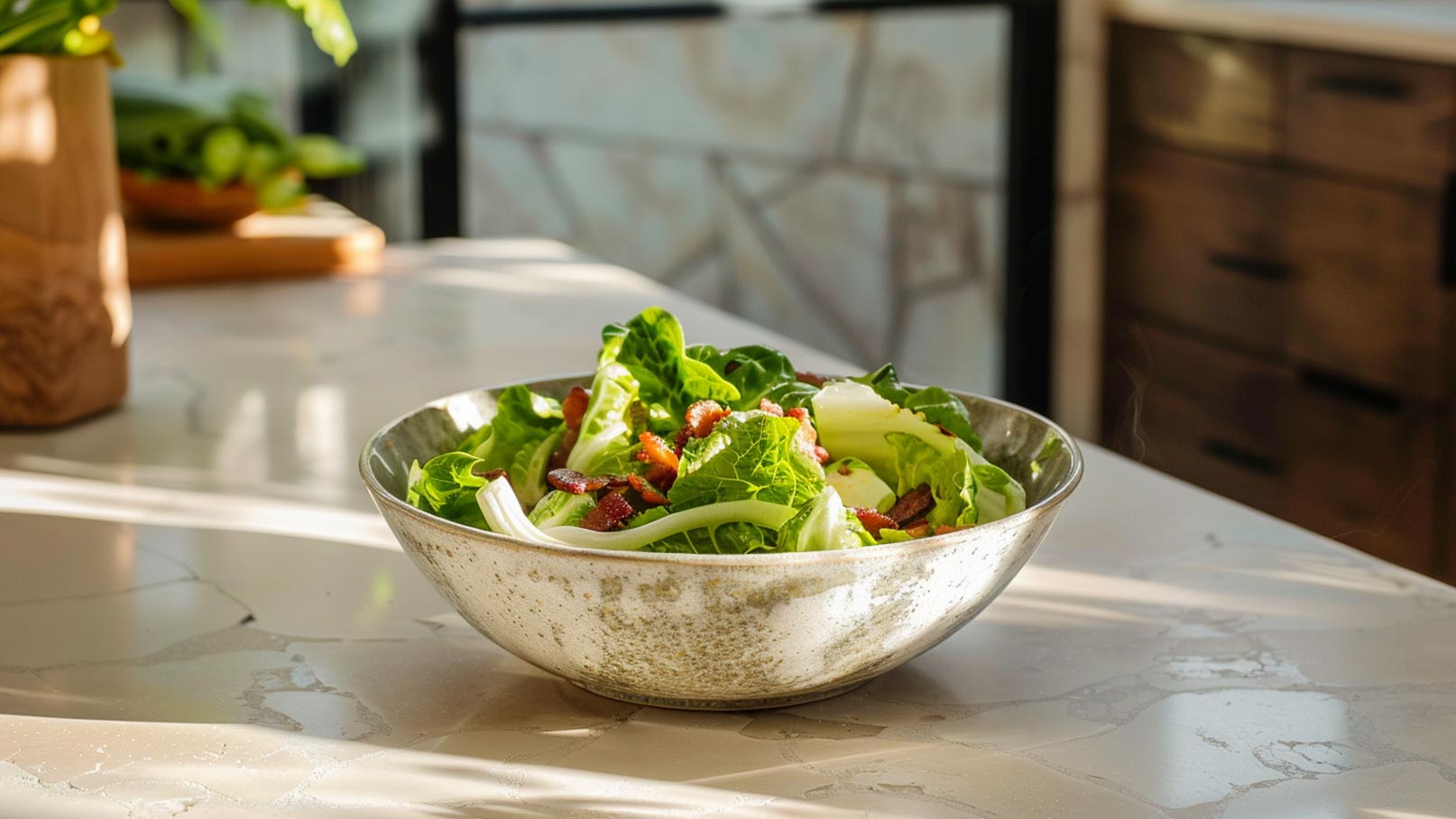 Eine silberne Schüssel mit frischem Salat, der aus grünen Salatblättern und kleinen Stückchen Bacon besteht. Der Salat steht auf einer hellen, marmorierten Arbeitsfläche und wird von sanftem Licht beleuchtet.