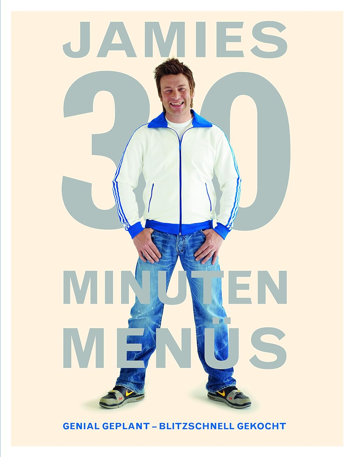 Das Bild zeigt einen lächelnden Mann in einer weißen Jacke mit blauen Akzenten und Jeans. Hinter ihm steht der Titel „Jamies 30 Minuten Menüs“ in großen Buchstaben. Unterhalb des Titels steht „Genial geplant – blitzschnell gekocht“.