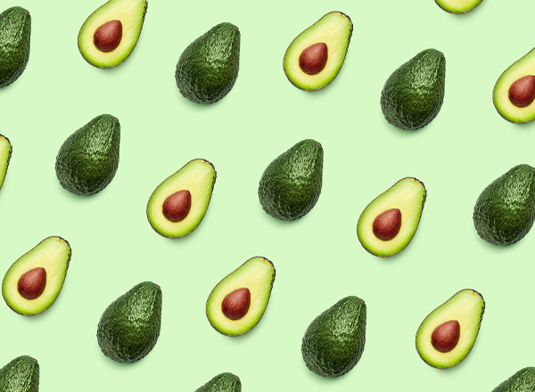 Eine gleichmäßige Anordnung von Avocados auf einem hellgrünen Hintergrund. Einige Avocados sind ganz, während andere halbiert sind, wobei die braunen Kerne sichtbar sind. Die Frucht ist in verschiedenen Positionen dargestellt.