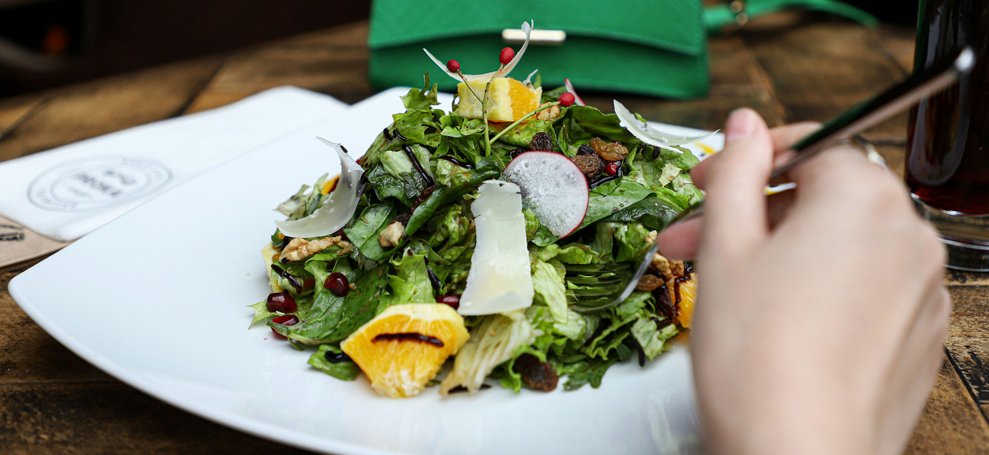 Eine Hand hält geschnittene Zwiebelstücke, die nach unten fallen. Im Hintergrund ist eine grüne Schüssel zu sehen. Der Fokus des Bildes liegt auf der Zubereitung von Zutaten für das Kochen.