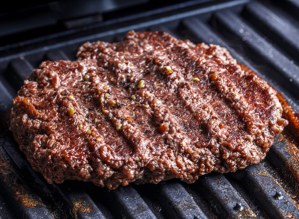 Ein gegrilltes Rindersteak liegt auf einem Grillrost. Die Oberfläche ist gut gebräunt mit grilltypischen Streifen, und es sind einige Gewürze sichtbar. Das Steak wirkt saftig und appetitlich.
