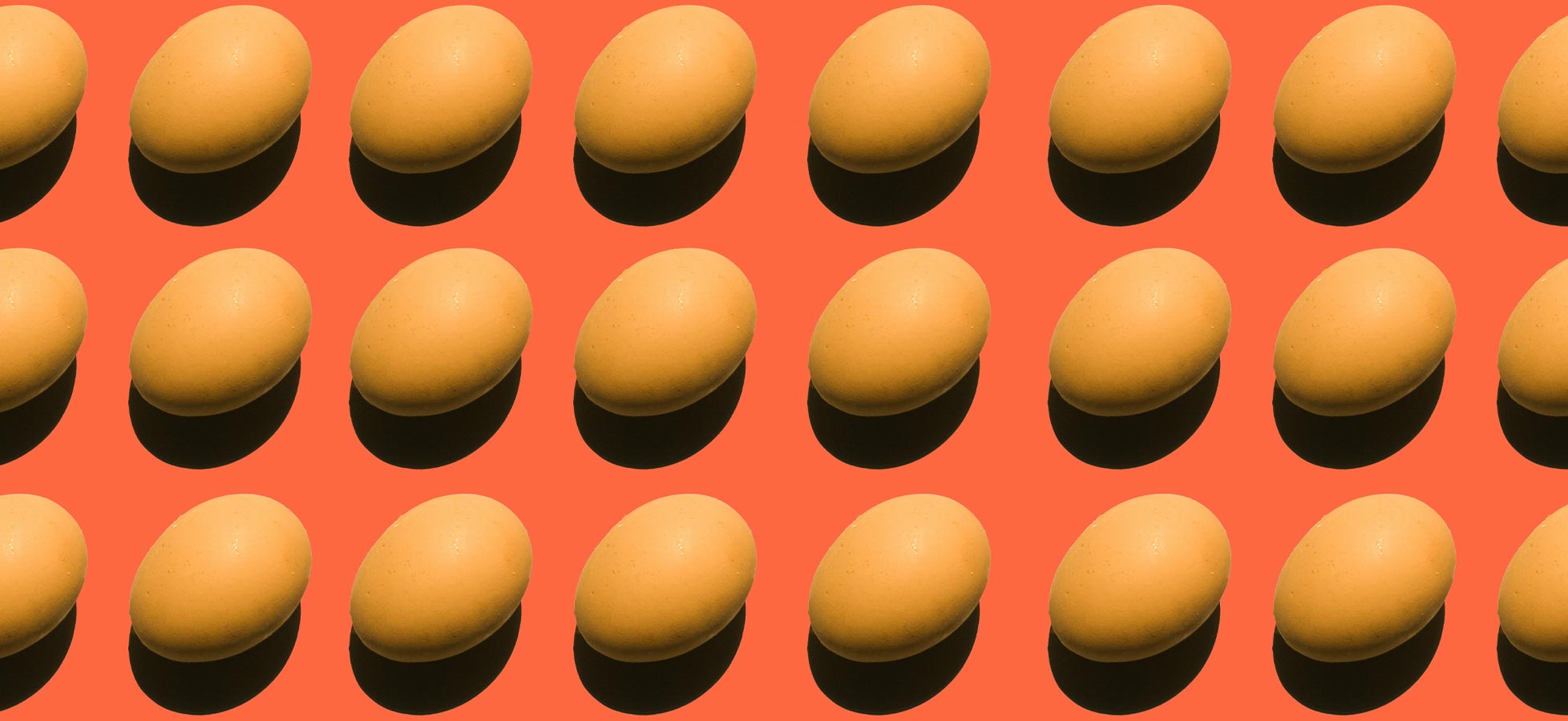 Das Bild zeigt eine wiederholte Anordnung von Eiern auf einem orangefarbenen Hintergrund. Die Eier sind in verschiedenen Positionen angeordnet, sodass einige einen Schatten werfen, was eine interessante visuelle Tiefe erzeugt.