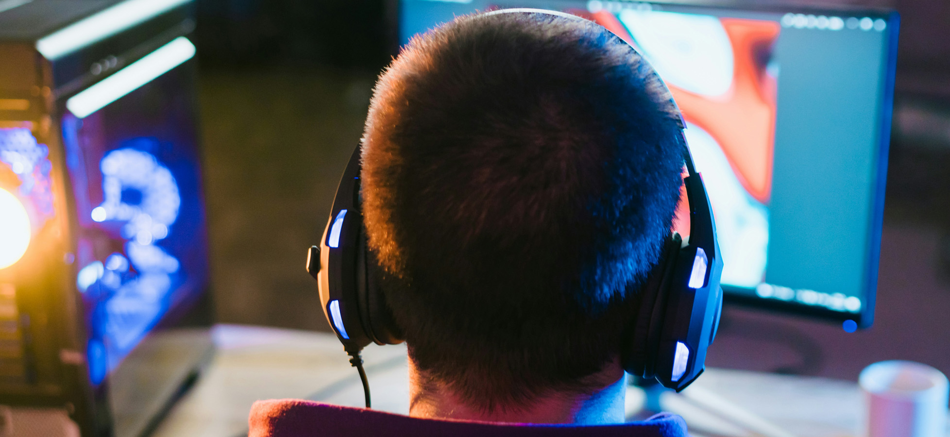 Eine Menschenmenge bei einem Festival. Im Vordergrund steht eine Person mit einem Dutt, die auf die Bühne schaut. Im Hintergrund sind dekorative Elemente und andere Festivalbesucher, die trinken und Spaß haben. Die Szene vermittelt eine lebendige, festliche Atmosphäre.