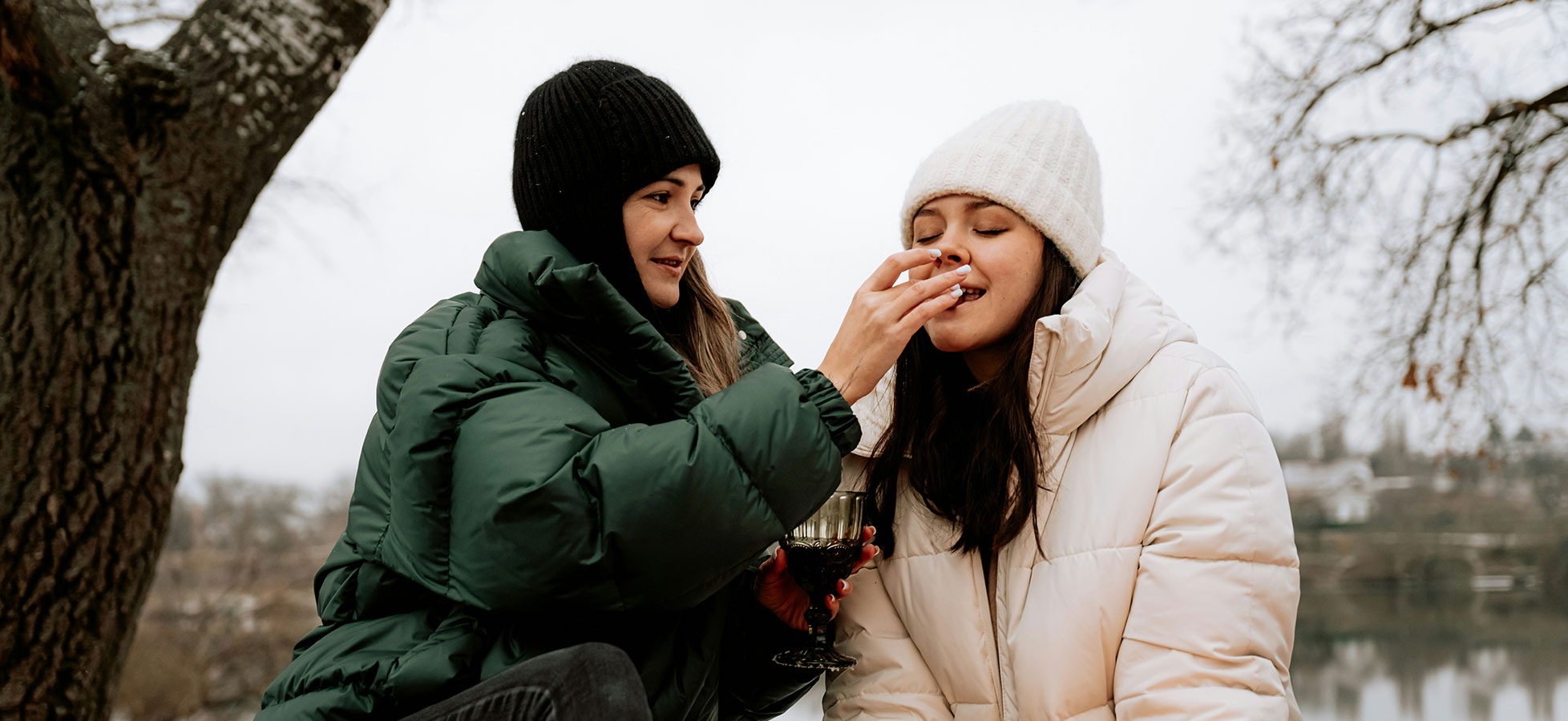 Eine junge Frau trägt einen schwarzen Hut und genießt einen Burger. Sie konzentriert sich darauf, den Burger zu essen, während sie ihre Augen schließt. Ihre Hände umschließen das Essen, und sie scheint den Geschmack zu genießen.