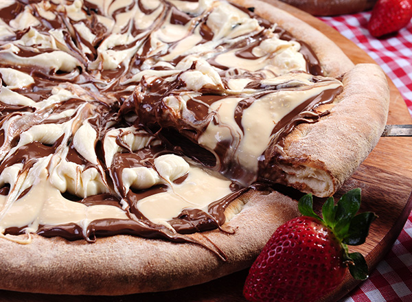 Ein köstlicher Schokoladenkuchen mit einer cremigen weißen Schokoladensauce, die spiralförmig auf der Oberfläche angeordnet ist. Ein Stück wurde herausgenommen, und frische Erdbeeren liegen daneben auf einem hölzernen Teller. Der Hintergrund zeigt ein kariertes Tuch.