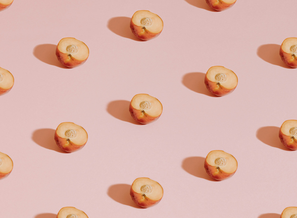 Die Bildkomposition zeigt mehrere halbierte Äpfel in gleichmäßigen Abständen auf einem rosa Hintergrund. Jeder Apfel ist in der Mitte klar sichtbar, wobei das Fruchtfleisch und die Kerne hervorgehoben sind. Die Darstellung vermittelt eine frische und ansprechende Fruchtästhetik.