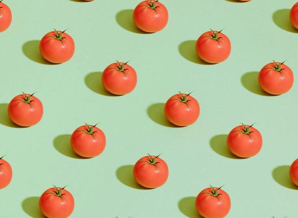 Ein Muster aus leuchtend roten Tomaten auf einem hellgrünen Hintergrund. Die Tomaten sind gleichmäßig verteilt und von einer glatten Oberfläche umgeben, was eine frische und lebendige Atmosphäre schafft.
