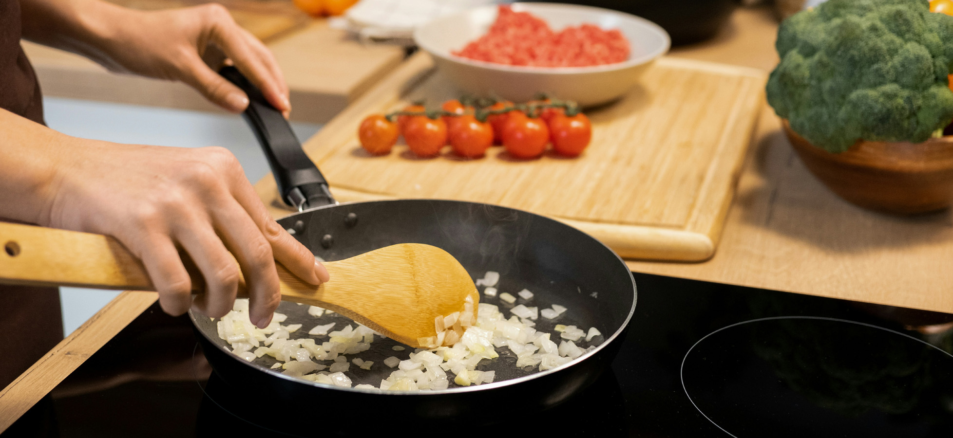 Ein Laib frisches Brot, teilweise in Scheiben geschnitten, liegt auf einem Holztisch. Daneben stehen eine dunkle Glasflasche und verschiedene Holzbehälter. Der Hintergrund ist hell und schlicht, um den Fokus auf das Brot zu lenken.