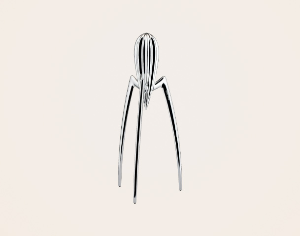 Eine stilisierte, silberne Skulptur, die einem hohen, schmalen Wesen ähnelt. Der obere Teil weist vertikale Rillen auf, während die Beine schmal und geradlinig sind. Die Figur steht aufrecht auf einem neutralen, hellen Hintergrund.