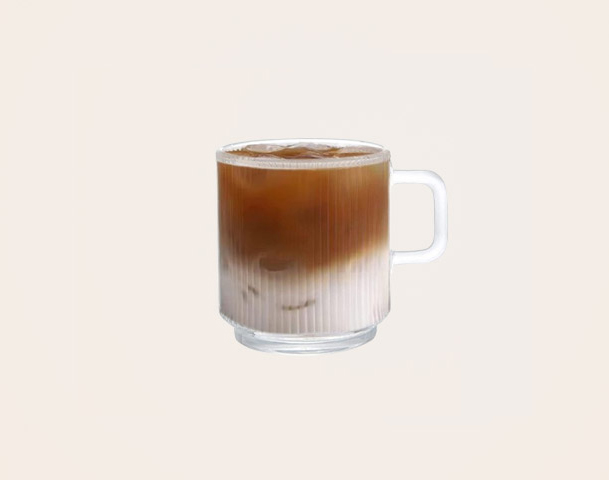 Ein halb gefüllter, transparenter Glasbecher enthält ein geschichtetes Getränk mit einer dunklen Oberseite und einer helleren unteren Schicht. Im Hintergrund sind vier weitere leere Becher abgebildet. Der Fokus liegt auf dem gefüllten Becher in der Mitte.