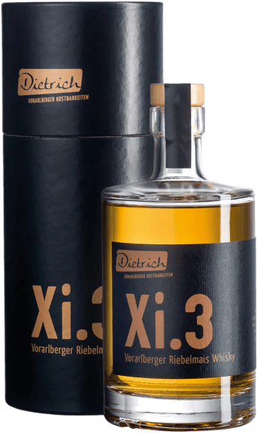 Eine Flasche Vorarlberger Riebelmais Whisky steht in einer schwarzen Verpackung. Die Flasche ist mit einem Holzstopfen verschlossen und trägt ein Etikett mit der Aufschrift "Dietrich Xi.3". Der Whisky hat eine goldene Farbe und die Verpackung ist schlicht gehalten.