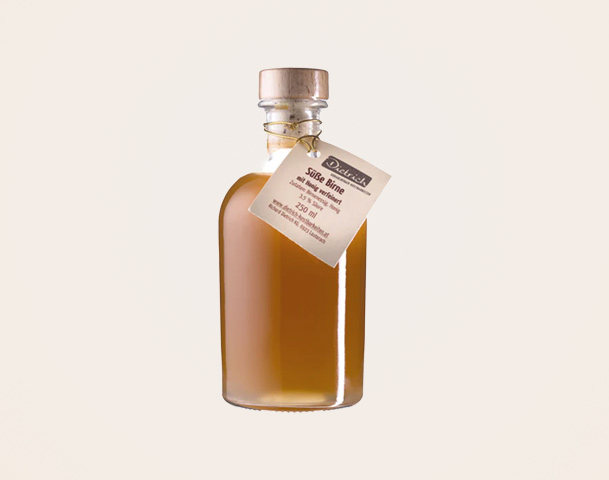 Eine klare Flasche mit einem Holzverschluss, gefüllt mit einer bernsteinfarbenen Flüssigkeit. An der Flasche hängt ein Etikett mit der Aufschrift „Süße Birne“ und Angaben zu Inhalt und Hersteller.