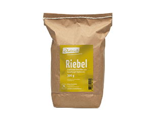 Braune Papiertüte mit grün-gelbem Etikett: Markenname "Dietrich", Produktname "Riebel" und Inhaltsangabe 300 g.