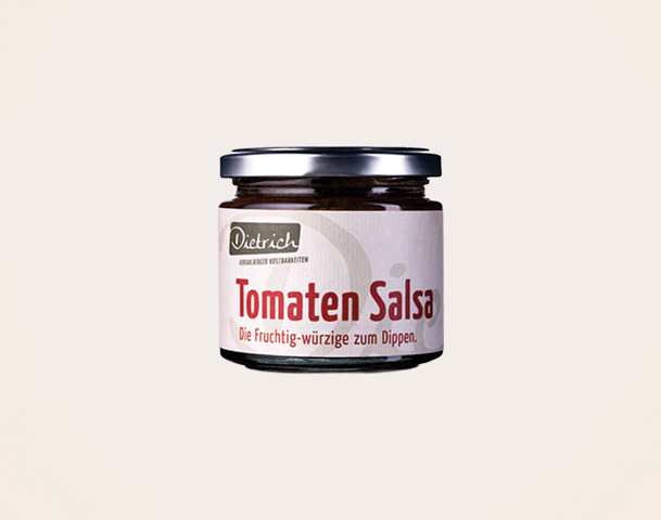 Ein Glas mit Tomatensalsa steht im Fokus. Das Etikett beschreibt die Salsa als fruchtig-würzige Dip-Option und zeigt den Markennamen „Dietrich“. Der Hintergrund ist einheitlich hell, um die Aufmerksamkeit auf das Produkt zu lenken.