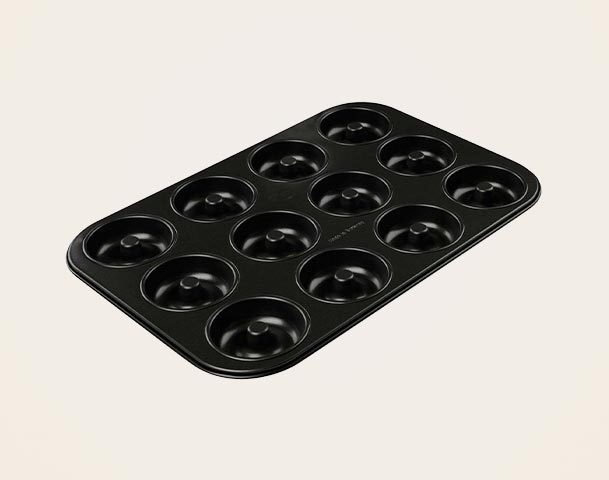 Eine schwarze Backform mit zwölf Vertiefungen für Donuts. Die Form hat abgerundete Kanten und ein einfaches, elegantes Design, geeignet zum Backen und für die Zubereitung von Donuts.