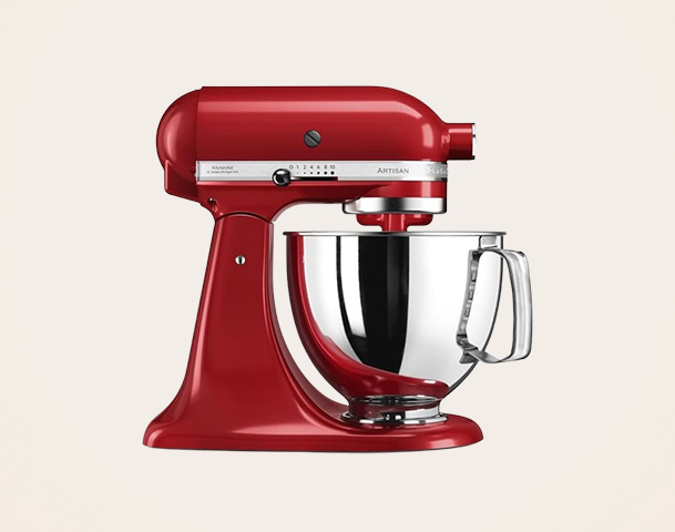 Eine rote Küchenmaschine steht auf einer neutralen Fläche. Sie hat eine glänzende Edelstahl-Schüssel mit einem Henkel und einen runden Mischaufsatz. Die Maschine verfügt über verschiedene Steuerknöpfe zur Anpassung der Mischgeschwindigkeit.