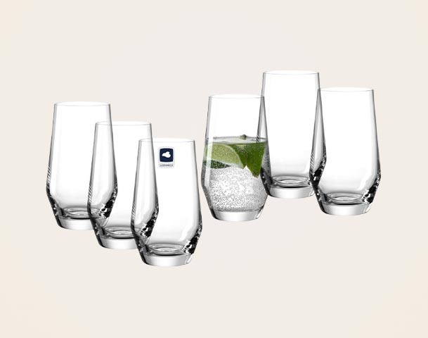 Ein Set aus sechs eleganten Gläsern, wobei eines ein Getränk mit Sprudel und Limettenscheiben enthält. Die Gläser haben eine moderne Form und sind aus klarem Glas.