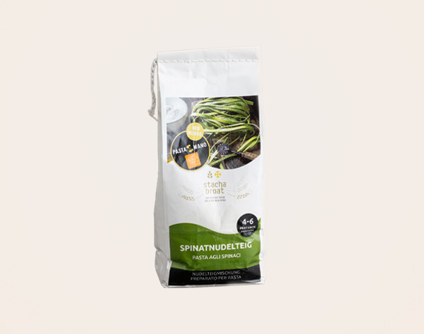 Eine Verpackung mit grünem und weißem Design für Spinatnudelteig. Der Text auf der Vorderseite beschreibt das Produkt als "Pasta agli spinaci" und enthält Zubereitungshinweise. Die Packung ist auf eine Kochzeit von 4-6 Minuten ausgelegt.