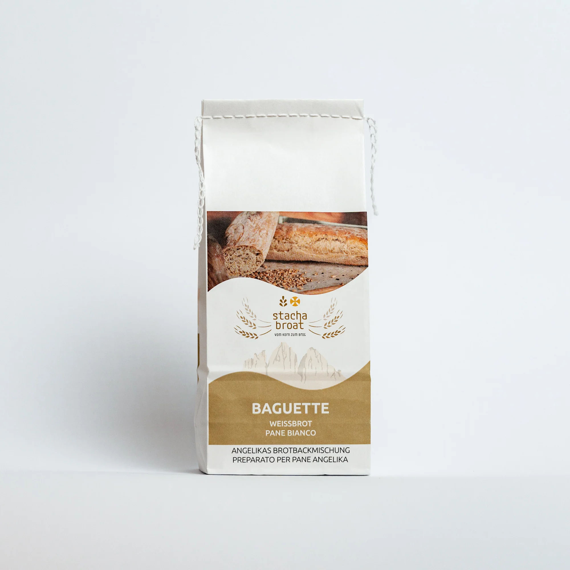Eine Tüte mit der Aufschrift „Baguette“ in deutscher, englischer und italienischer Sprache. Die Verpackung zeigt ein Bild von Baguette-Stangen. Sie ist hell gestaltet und hat ein minimalistisches Design, das durch eine goldene Farbe und graue Bergsilhouetten ergänzt wird.