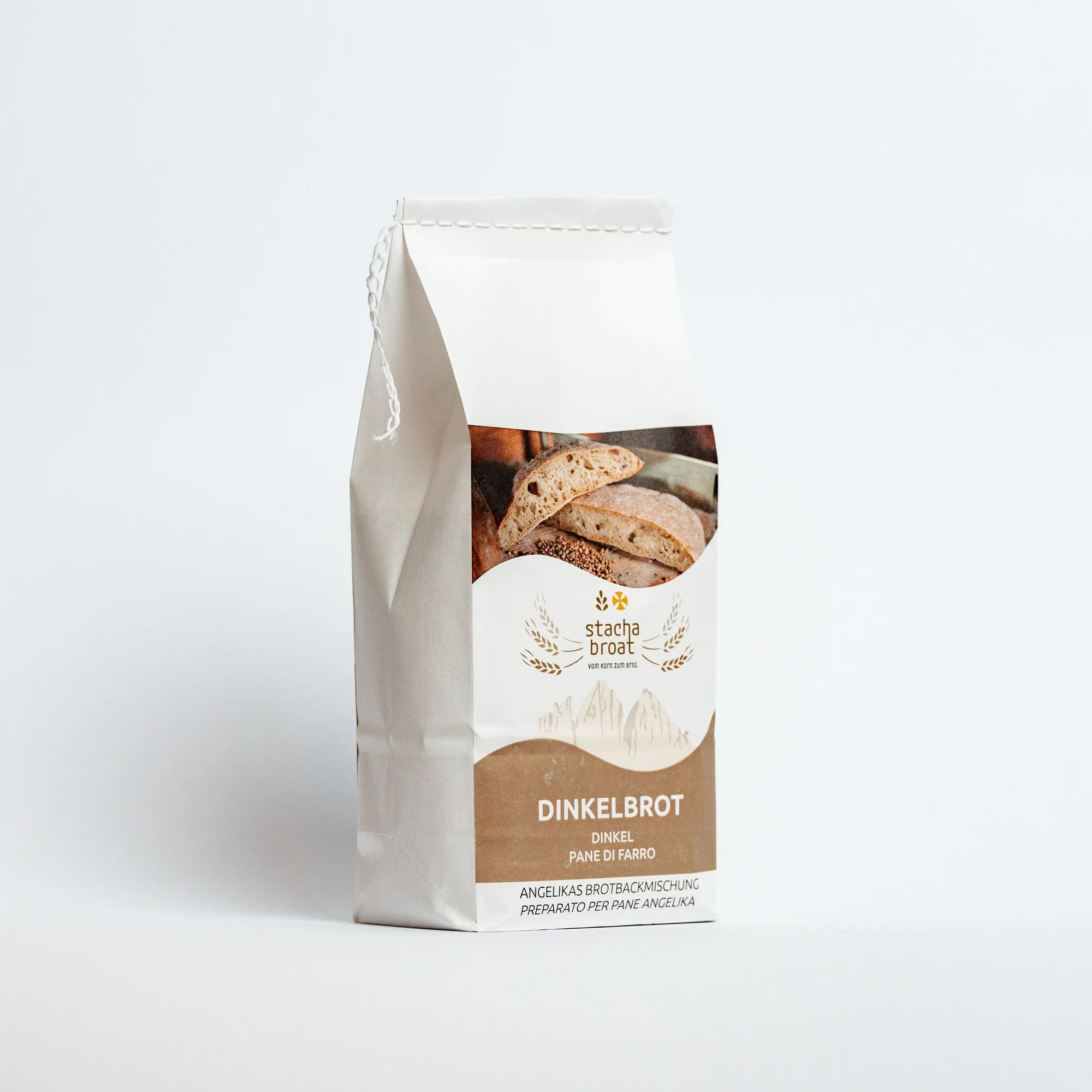 Eine Tüte Dinkelbrotmischung steht auf einem weißen Hintergrund. Auf der Vorderseite der Tüte ist ein Bild von Brotscheiben, zusammen mit dem Text "DINKELBROT" in kräftigen Buchstaben, sowie der Markenname "stacha broat". Die Verpackung wirkt modern und ansprechend.