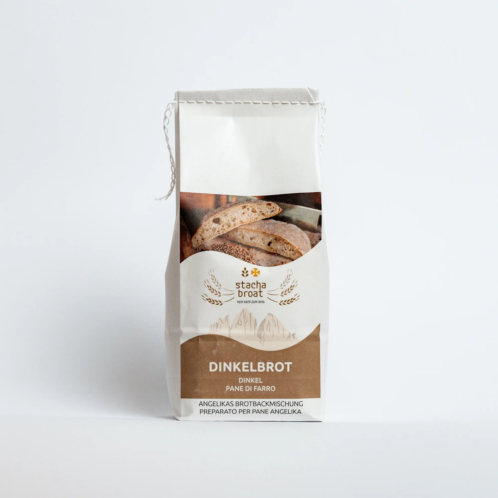 Eine Packung Dinkelbrotmischung steht auf einem weißen Hintergrund. Auf der Vorderseite ist das Wort "Dinkelbrot" sowie ein Bild von Brotscheiben abgebildet. Das Design ist schlicht und modern, mit goldenen Akzenten und dem Markennamen „stacha broat“.