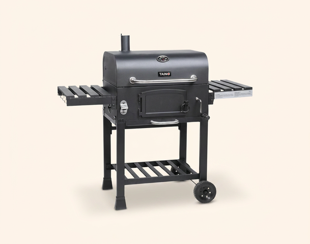 Ein schwarzer Grill mit zwei seitlichen Ablageflächen und einem Untergestell auf Rollen. Der Grill hat eine geschlossene Kammer mit einer Tür und einem Kamin auf der Oberseite. Die Konstruktion ist stabil und eignet sich für das Grillen im Freien.