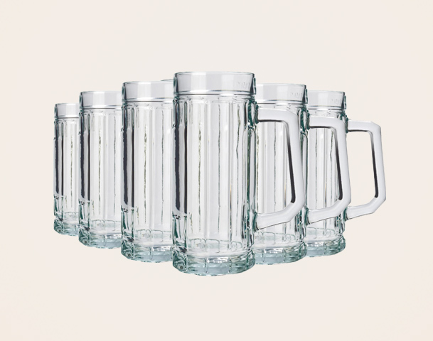 Sechs gläserne Bierkrüge stehen in einer Reihe. Die Krüge haben eine gerippte Oberfläche und eine stabile Henkel. Sie sind leer und reflektieren das Licht, was ihnen ein klareres Aussehen verleiht. Der Hintergrund ist einfarbig und hebt die Krüge hervor.