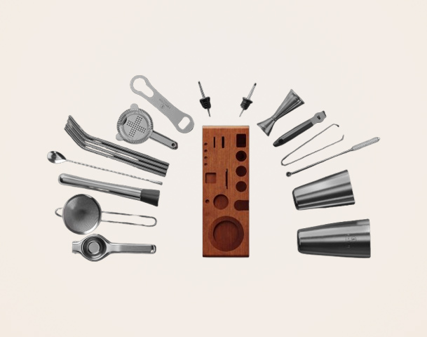 Ein Set aus verschiedenen Cocktail-Equipments und Zubehör, darunter Shaker, Messbecher, Siebe und ein Holzständer mit Einsätzen für die Utensilien. Die Werkzeuge sind aus Edelstahl und sind gleichmäßig um den Ständer angeordnet.