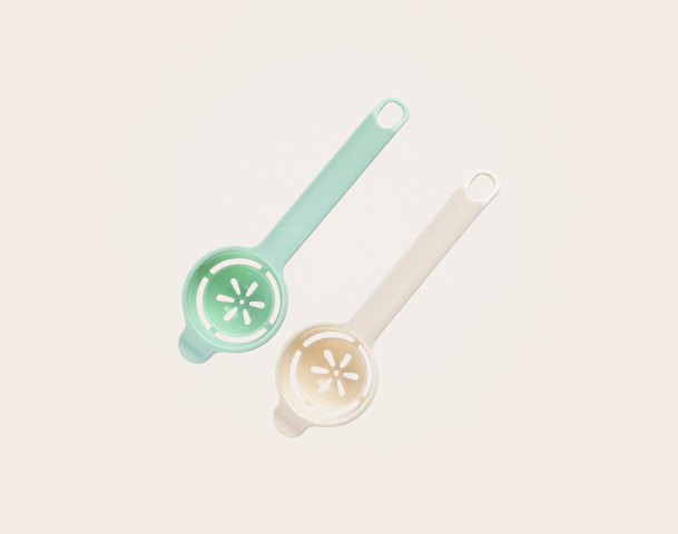 Das Bild zeigt zwei farblich unterschiedliche Eiertrenn-Tools in Mint und Cremefarben. Eines wird verwendet, um ein Ei in eine Schüssel zu trennen. Die Werkzeuge haben einen runden Boden mit kleinen Löchern zur effektiven Trennung von Eiweiß und Eigelb.