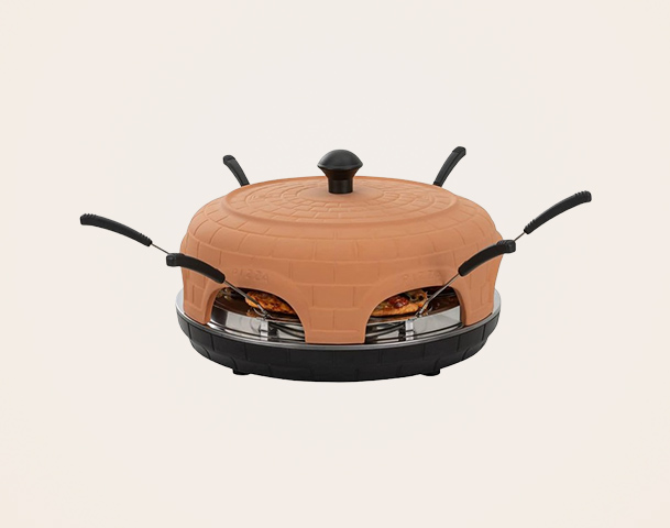 Ein runder Raclettegrill mit einem terrakottafarbenen Deckel und mehreren langen Griffen. Der Grill hat eine flache Oberfläche mit darunterliegenden Kochflächen für das Zubereiten von Käse und anderen Lebensmitteln. Die Form ist robust und speziell für gesellige Mahlzeiten konzipiert.