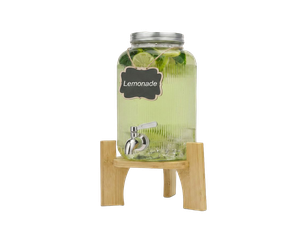 Glas-Limonadenbehälter mit Zapfhahn auf Holzständer, gefüllt mit hellgelber Limonade, Zitronenscheiben und Minzblättern; kleines Schild mit der Aufschrift "Lemonade".