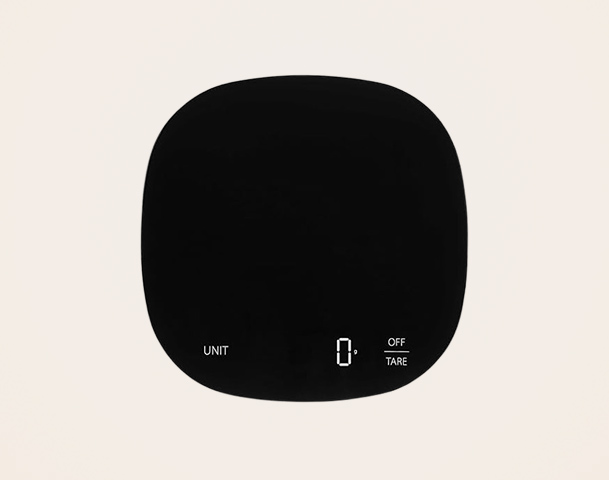 Eine schwarze digitale Waage mit einem runden Design und weißen Anzeigeelementen. Auf der Waage sind die Tasten „UNIT“, „OFF“ und „TARE“ sowie eine digitale Anzeige mit der Zahl „0“ sichtbar.