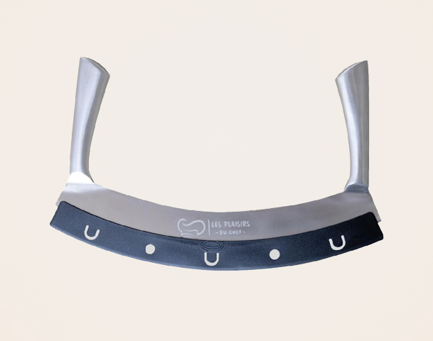 Das Bild zeigt ein halbmondförmiges Küchenwerkzeug mit einem glänzenden, metallischen Klingenbereich und zwei ergonomischen Griffen. An der unteren Kante befinden sich eine schwarze Gummibeschichtung und mehrere kleine Löcher zur Handhabung.