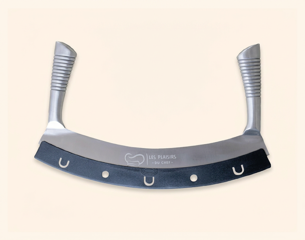 Das Bild zeigt ein halbmondförmiges Küchenwerkzeug mit einem glänzenden, metallischen Klingenbereich und zwei ergonomischen Griffen. An der unteren Kante befinden sich eine schwarze Gummibeschichtung und mehrere kleine Löcher zur Handhabung.