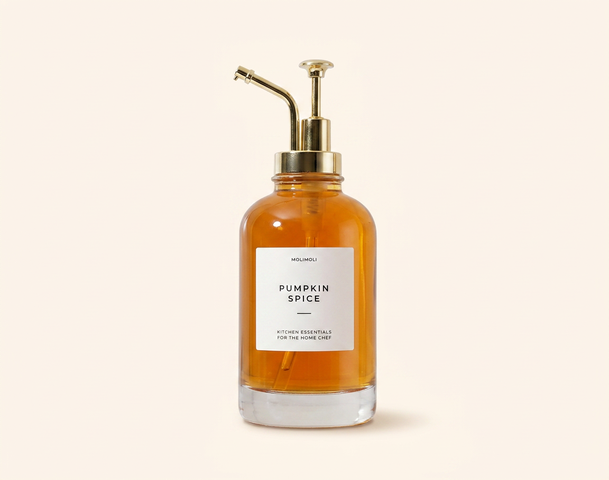 Zwei elegante Flaschen mit Pumpaufsätzen, eine orange mit der Beschriftung „Pumpkin Spice“ und eine transparente mit der Aufschrift „Vanilla“. Beide Flaschen haben goldene Details und stehen vor einem hellen Hintergrund. Die Produkte scheinen für Raumdüfte oder ätherische Öle gedacht zu sein.