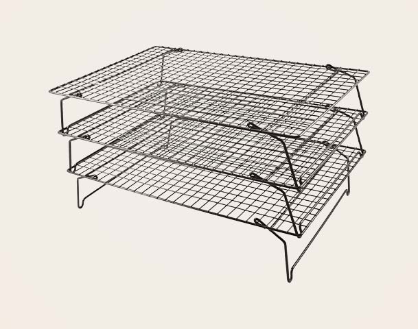 Ein dreistufiges Gitterregal aus Metall. Die Regale sind aus feinen, kreuzförmigen Drähten gefertigt und bieten eine stabile Unterlage. Es ist in der Mitte offen, um eine gute Luftzirkulation zu ermöglichen, und auf abgewinkelten Beinen montiert, die dem Regal Halt geben.