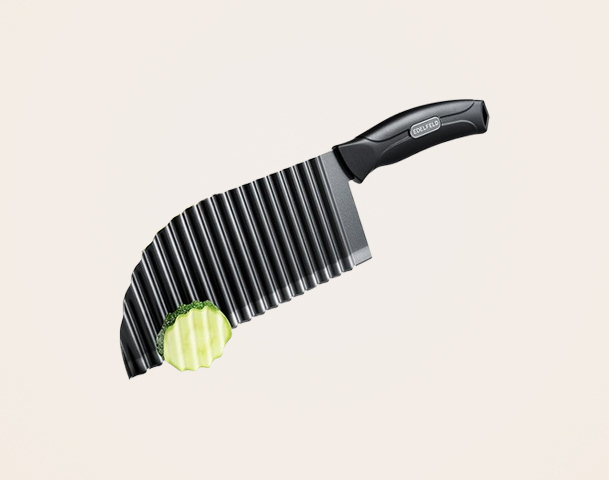 Ein gebogener Messerschneider mit einer gewellten Klinge schneidet eine grüne Zucchini in gleichmäßige Scheiben. Der Griff des Messers ist schwarz und ergonomisch gestaltet.