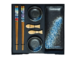 Schwarzes Geschenkset mit japanischem Keramikgeschirr: rechteckiger Saucenteller, zwei kleine Schalen, ein Paar Holz-Essstäbchen mit bunten Griffen und zwei fischförmige Stäbchenhalter.