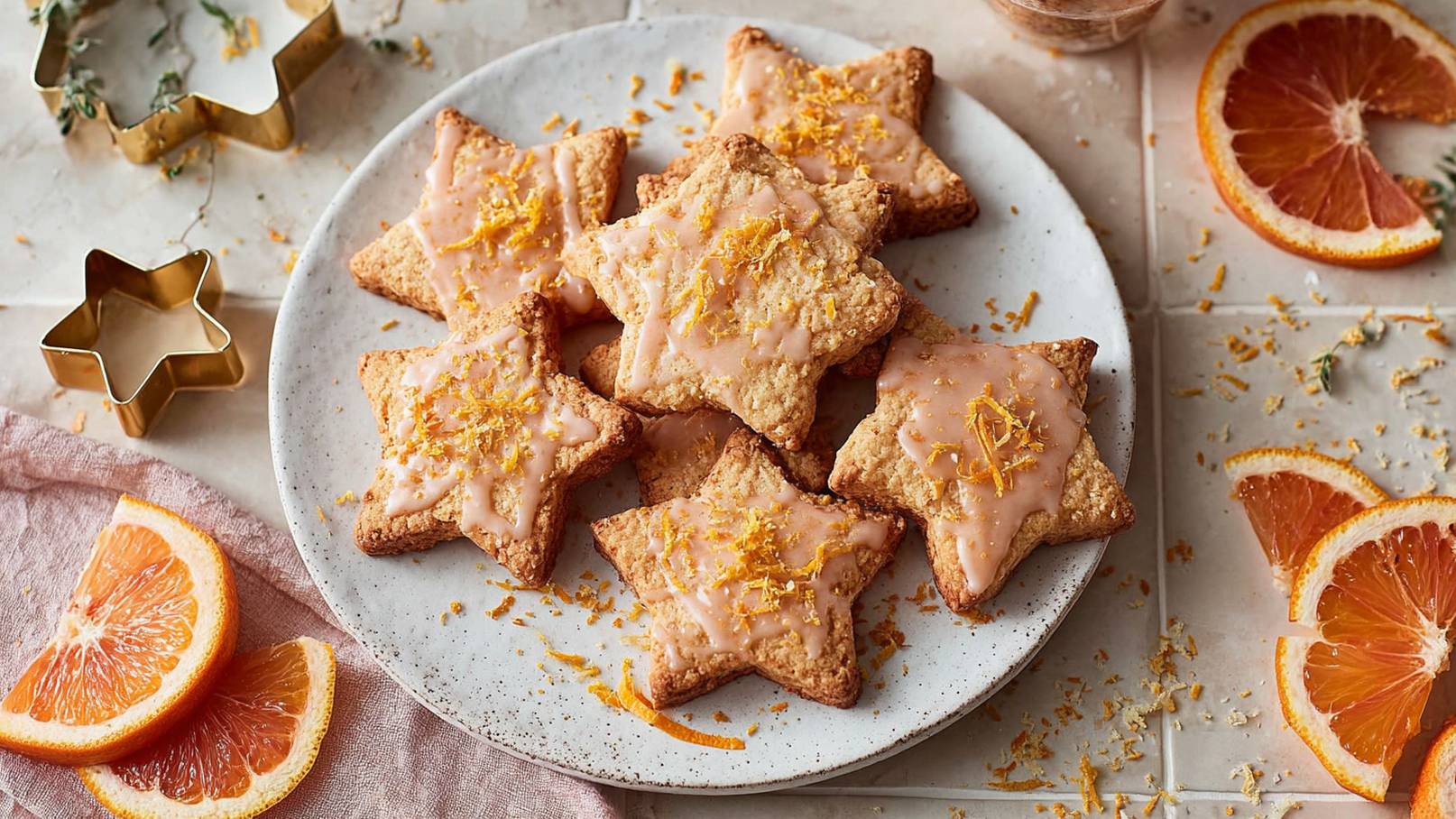 Das Bild zeigt eine ansprechende Anordnung von zwei leuchtenden Orangensternen, umgeben von aromatischen Zimtstangen und ganzen Nelken. Die warmen, erdigen Farben der Gewürze bilden einen schönen Kontrast zu den leuchtenden Sternen. Im Hintergrund ist eine getrocknete Orangenscheibe platziert, die dem Arrangement eine rustikale und festliche Note verleiht.
