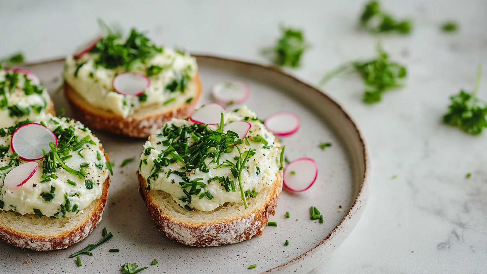 Auf dem Bild sind drei köstliche Scheiben Brot mit einem aromatischen Kräuter-Ei Aufstrich zu sehen. Die Aufstriche sind großzügig mit dünnen Scheiben von knackigen Radieschen, cremiger Avocado, frisch gekochtem Ei und einer Vielzahl von duftenden Kräutern versehen. Die frischen Farben der Zutaten bilden einen lebendigen Kontrast auf dem Teller und verleihen dem Gericht eine ansprechende Optik.
