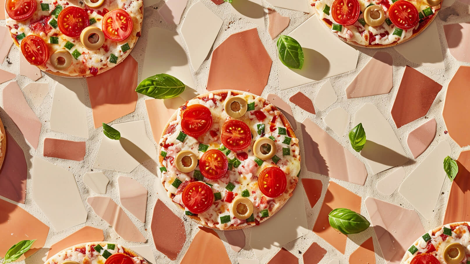 Eine Ansicht von mehreren Pizzen auf einem gemusterten Untergrund. Die Pizzen sind mit Kirschtomaten, Oliven, grünen Paprikawürfeln und frischem Basilikum belegt. Die lebhaften Farben und die verschiedenen Beläge verleihen den Pizzen ein appetitliches Aussehen.