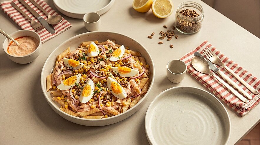 Große Schüssel mit Pommes frites, belegt mit Thunfisch, Mais, roten Zwiebeln, Erbsen, Vierteln hartgekochter Eier und Körnern.