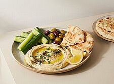 Image of Hummus-Plate mit Gurke, Oliven und Fladenbrot