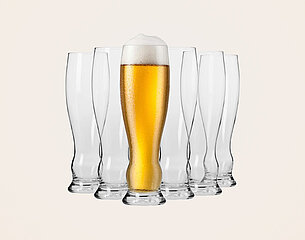 Ein gefülltes Glas mit goldenem Bier und einer Schaumkrone steht in der Mitte vor mehreren leeren Gläsern. Die Gläser sind in einer symmetrischen Anordnung angeordnet. Der Hintergrund ist einfarbig.