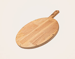 Ein ovales Pizzaschneidebrett aus Holz mit einem flachen Rand und einem Griff liegt neben einer Verpackung mit der Aufschrift "PIZZAMACHETE". Das Design der Verpackung ist schlicht und betont den Produktnamen.