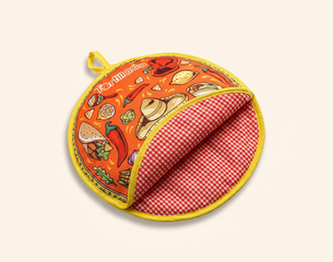 Runder Topflappen mit gelbem Rand: außen orange mit Tortilla- und Mexiko-Motiven (Tacos, Chili, Sombrero), innen rot-weiß kariert.