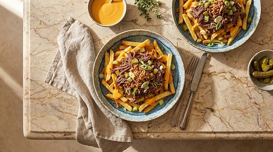 Zwei Schalen mit Pommes Frites, belegt mit würzigem Hackfleisch, geschmolzenem Käse und gehackten Frühlingszwiebeln.