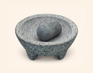 Grauer Granit‑Molcajete (dreibeiniger Mörser) mit einem zylindrischen Stößel in der Schale.