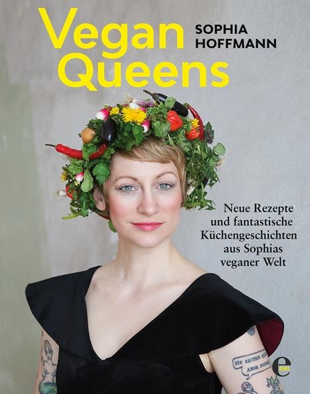 Das Bild zeigt eine Frau mit einem einzigartigen Blumenkranz, der aus Gemüse und Kräutern besteht. Sie trägt ein schwarzes Oberteil und lächelt. Im Hintergrund ist ein hellgrauer Wand sichtbar. Der Titel "Vegan Queens" und der Name "Sophia Hoffmann" sind prominent abgebildet.